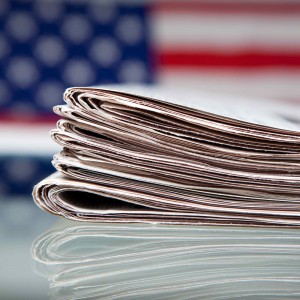 Photo - stack of newspapers in front of American flag